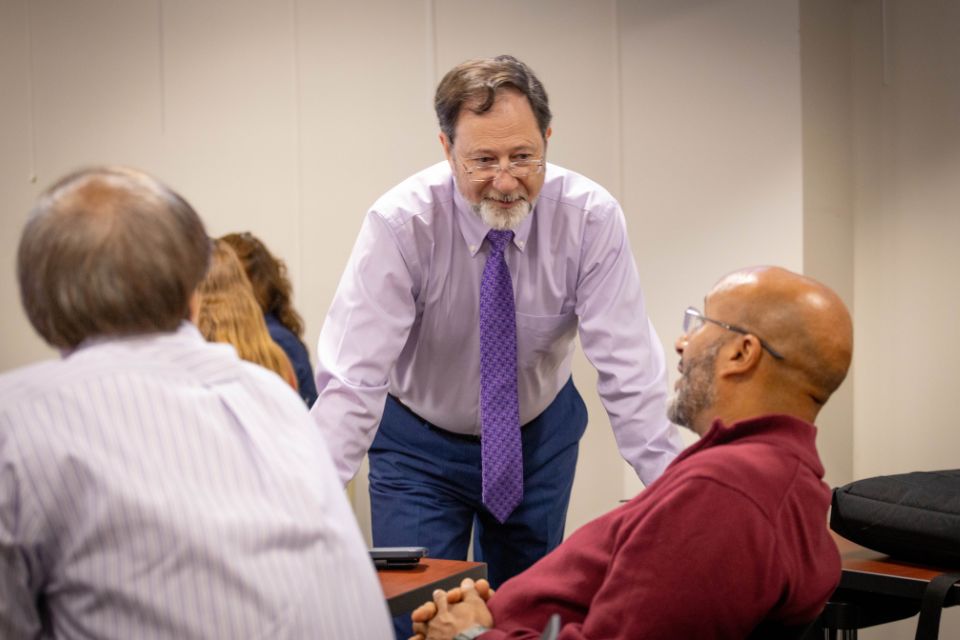A man standing and listening to participants