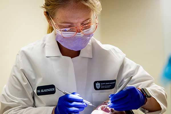 A close-up of a female dentist working in the mouth of a patient.
