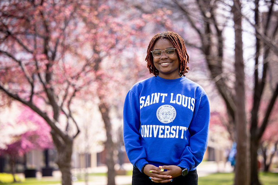 Malaisyah Vann Malaisyah Vann poses for a photo outside on campus with pink flowering trees behind her.
