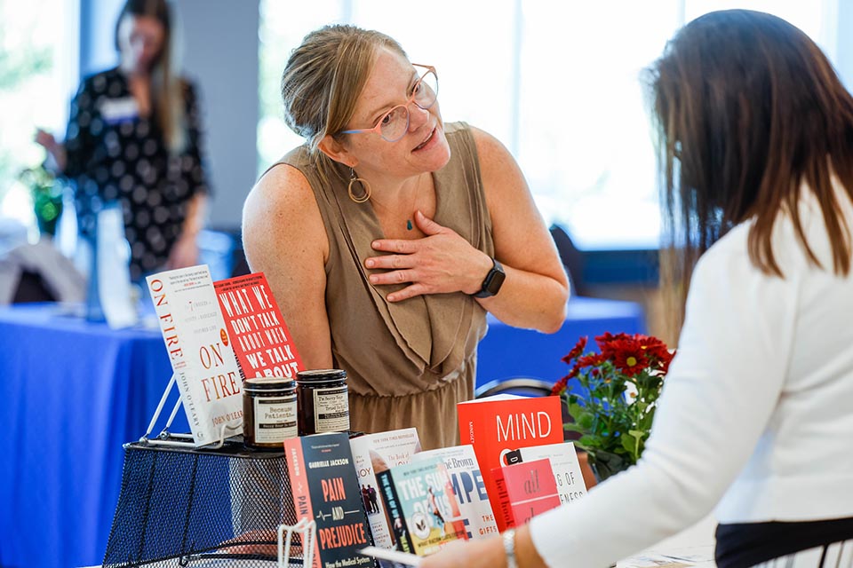 Employee resource fair Employee at a book fair in front of a table of books