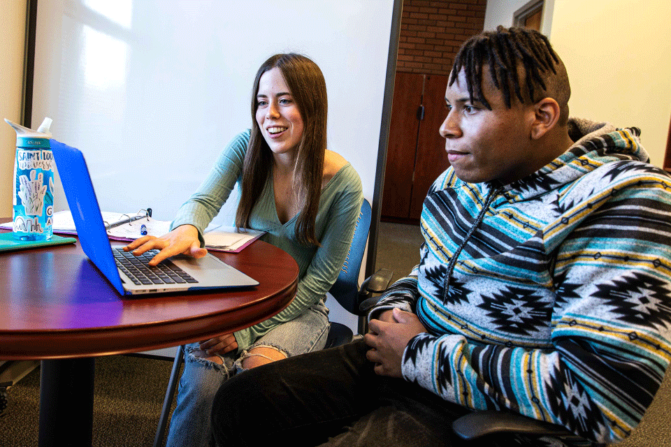 Students working to improve their study skills Two students sitting at a table looking at a computer