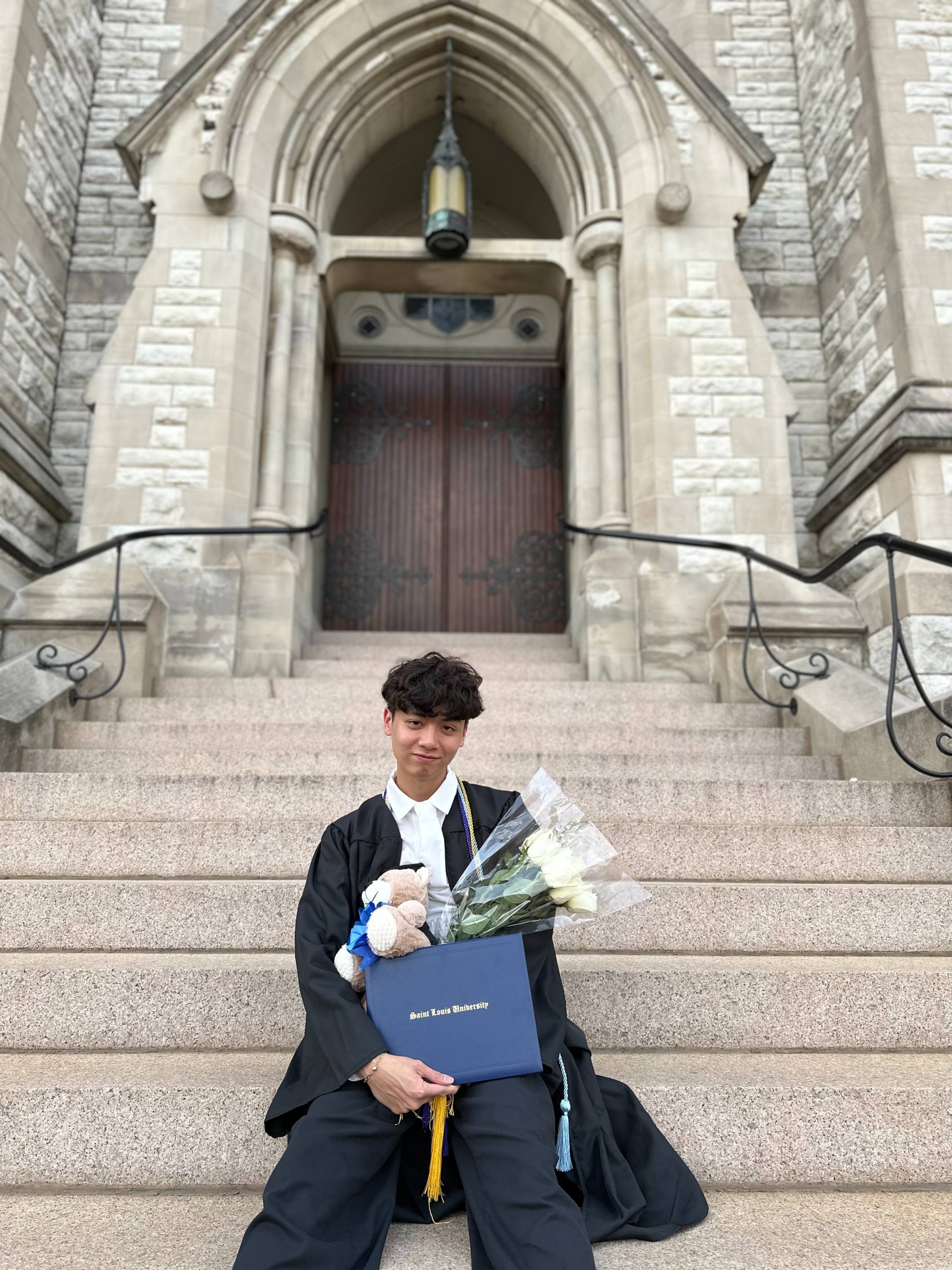 Jacob Mai Headshot male with dark features holding a diploma