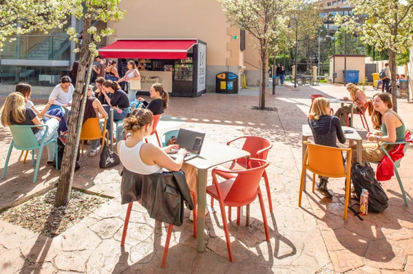 A student sits on a university campus patio, enjoying the warm Madrid weather and sunshine.