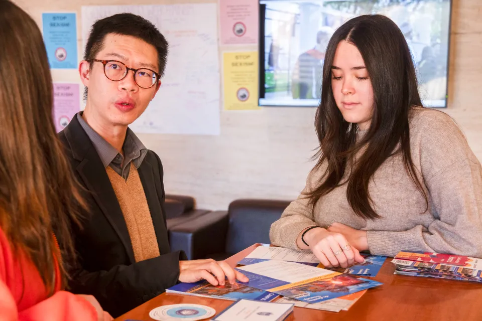 3 people consult information brochures in a building lobby.