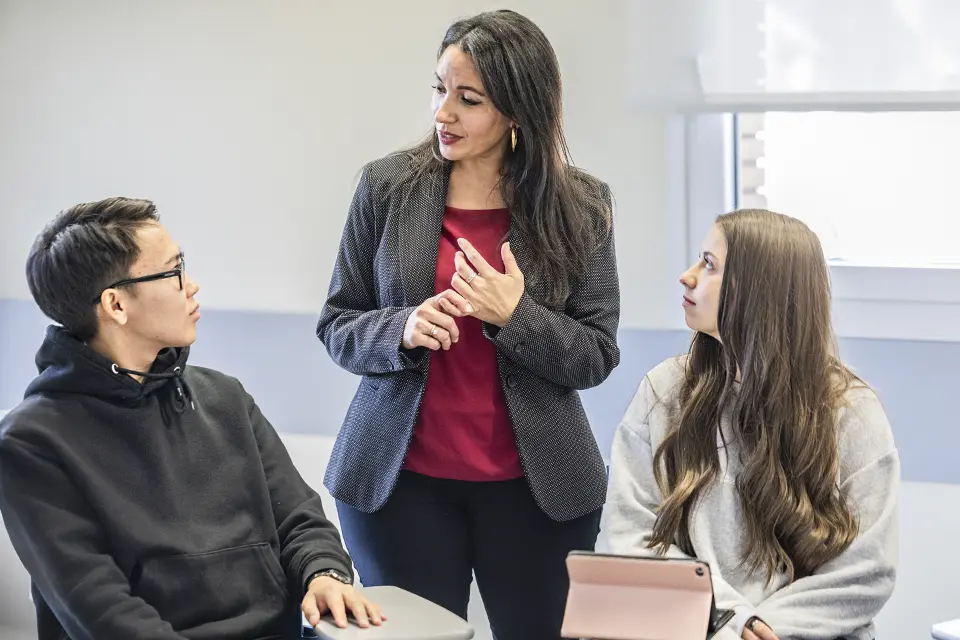 Two students in class talking with the professor. Two students in class talking with the professor.