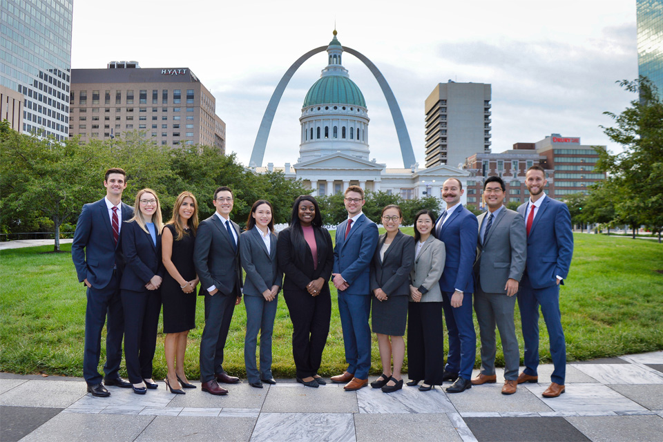Opthamology Residents 2024 A group of residents wearing suits stand in a row with the St. Louis arch and Old Courthouse in the background.