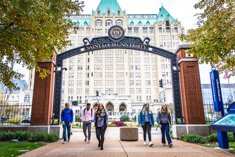 A group in front of the SLU sign on south grand A group in front of the SLU sign on south grand