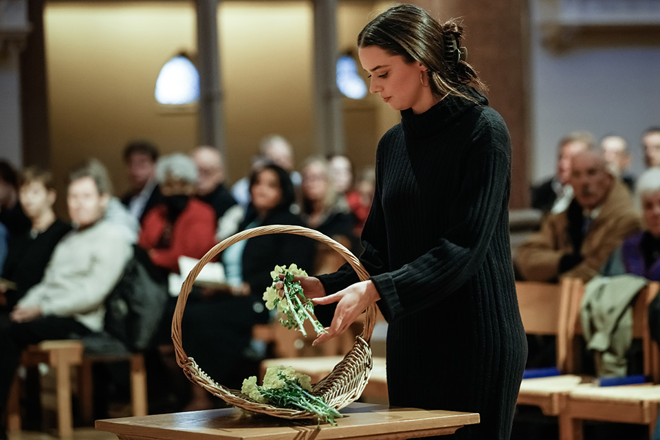 Mission and Identity Annual Events A young woman places flowers in a basket during a prayer service.