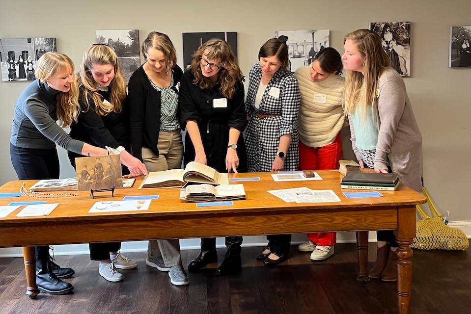 Group photo of SCAC researchers Group photo of SCAC researchers examining texts and other materials on a table.