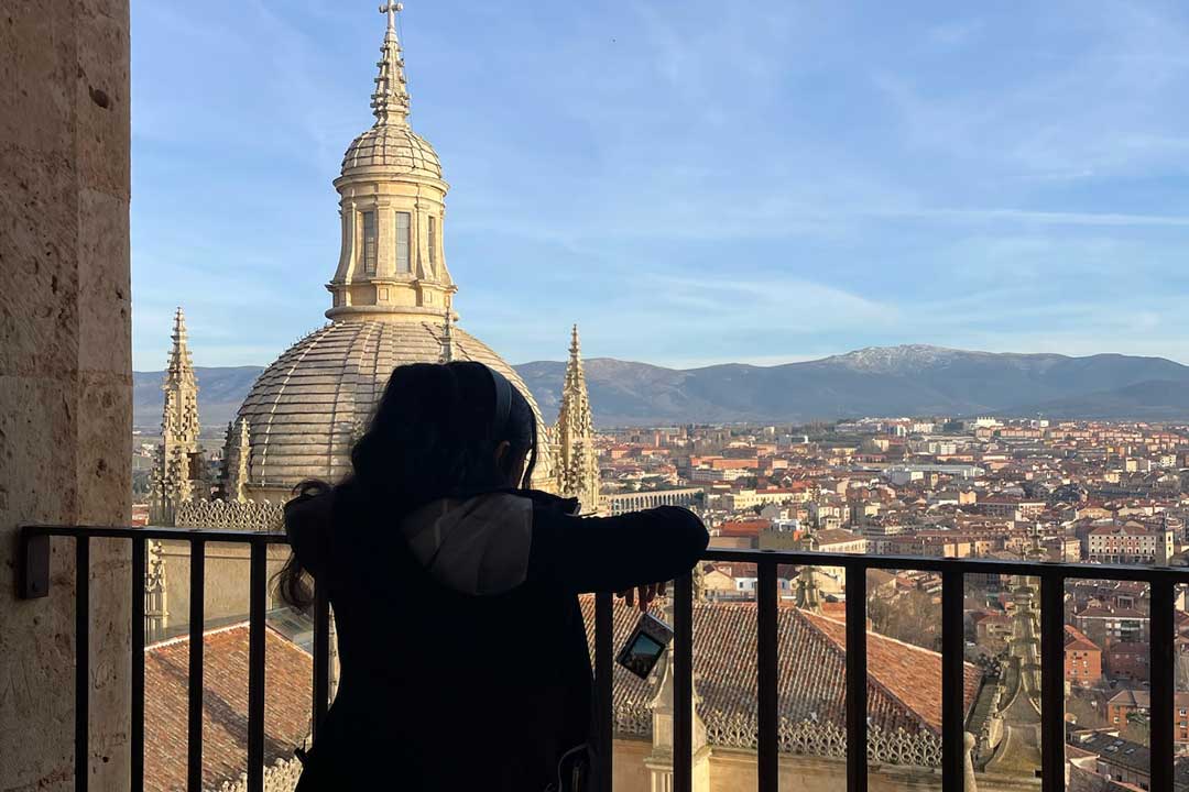 student silohuetted looks at aerial view of city